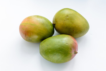 Three ripe mangoes on a white background. Mangoes are juicy stone fruit (drupe) from numerous species of tropical trees belonging to the flowering plant genus Mangifera. Tropical fruit.