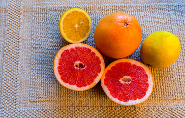 Handful of citrus grapefruit and patterns of its cut, all on gray color cloth