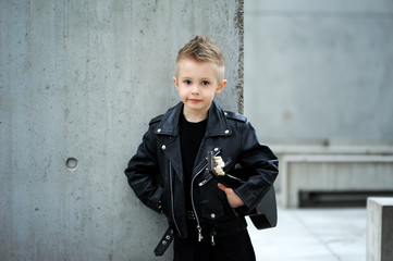 A handsome boy in black leather jacket, with  iroquois haircut, playing rock music on the guitar,...