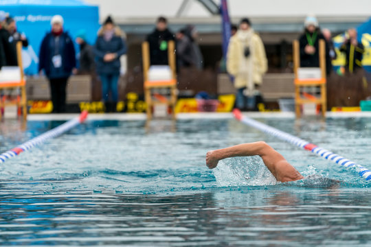 Man swimming, swim competition and spectators in the background