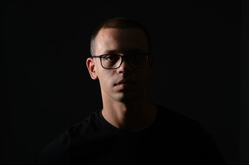 Obraz premium a man in a black jacket shows emotions in the Studio on a black background
