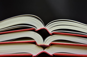 aufgeschlagene Bücher mit rotem Buchrücken übereinandergestapelt