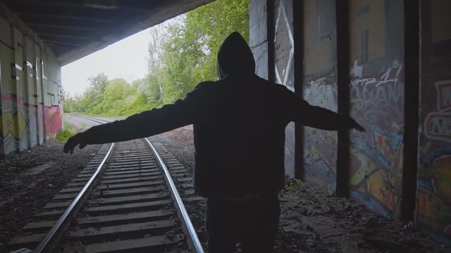 Man alone walking away on the railroad. Teenager balancing on train rail track