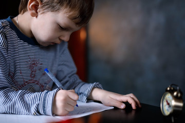 horizontal portrait of a boy while writing on a blue background
