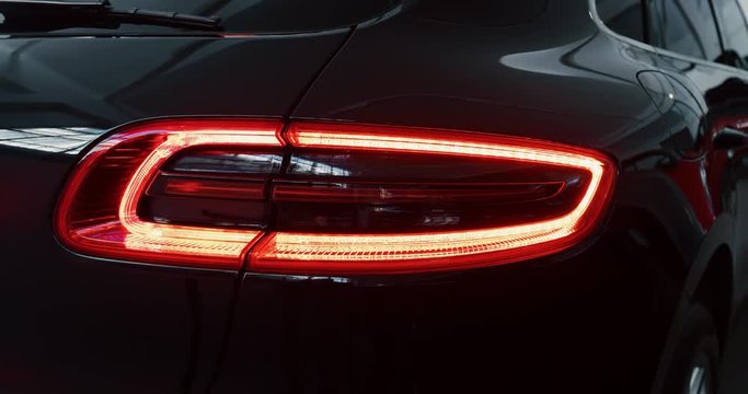 Close up of details of switched on tail lights of anonymous prestigious luxury modern car. Shot in 8K. Concept of passion for driving cars and engines, car dealerships, used cars,luxury cars,auto dial