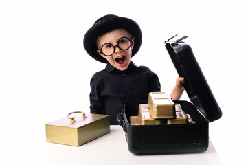 A little boy, 5 years old, plays with gold bars. He works in the bank as a security guard. The concept of wealth, earning and greed for money. Isolated on white.