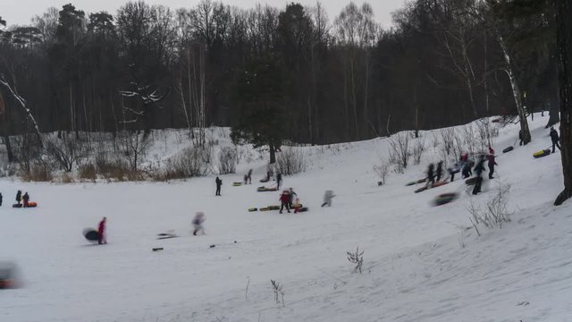 A lot of people go down the snow hill in the Park on a winter day off,time lapse