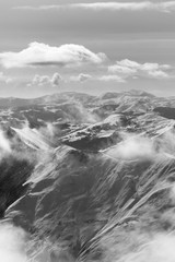 Black and white snowy sunlight mountains in haze and cloudy sky