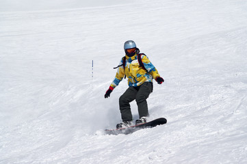 Fototapeta na wymiar Snowboarder descends on snowy ski slope at high winter mountains