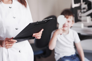 Woman with documents tests the visual acuity of little boy