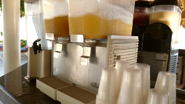 Dispensers making orange juice at hotel bar, nobody