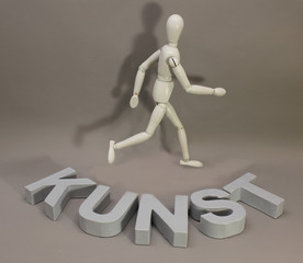 Das Wort KUNST aus Pappebuchstaben mit Gliederpuppe