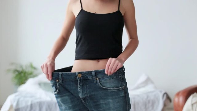 Fit young woman in loose jeans after losing weight