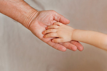 Kids hand over grandfather's hand on light background