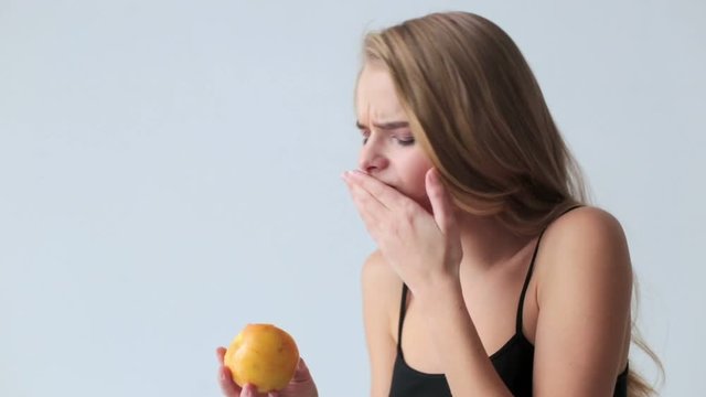 Young woman with sensitive teeth and apple