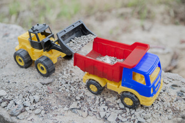 a toy tractor loads a toy dump truck