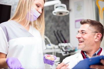 Obraz premium Mature male dentist discussing and talking with young female technician, working together in a dental clinic