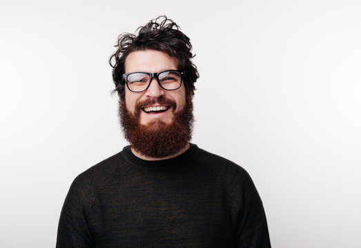 Handsome bearded boy in glasses smiles and looks at the camera