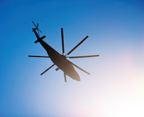 Naklejka na ściany i meble Silhouette of heavy transport helicopter flying against the blue sky
