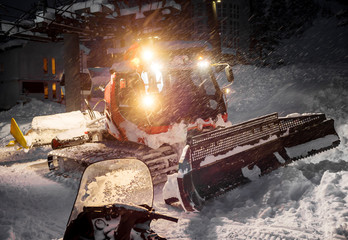 Snowcat preparing a slope at night in high mountains at skiing resort of the North Caucasus Elbrus