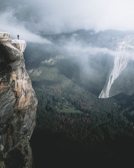 Man standing at edge of cliff over Yosemite Valley, California, USA