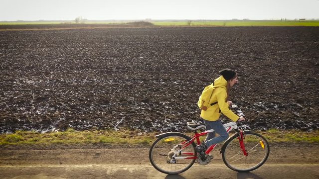 Aerial drone view girl rides bicycle on countryside road in yellow jacket