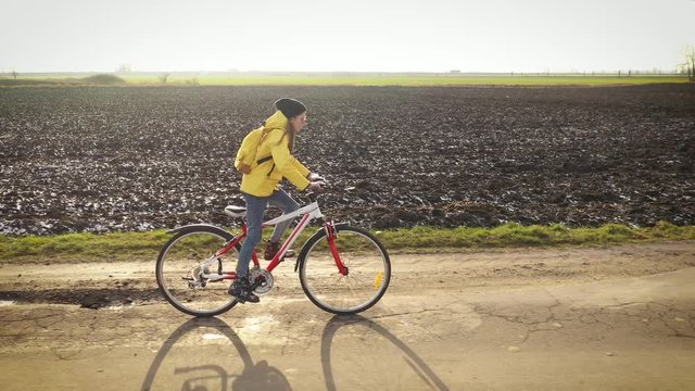 Aerial drone view girl rides bicycle on countryside road in yellow jacket