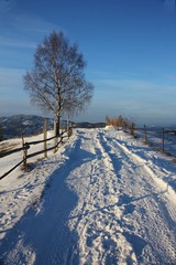  Country road covered with snow on the hills, with blue sky in the background. 