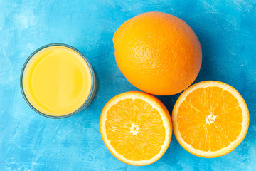 Orange fresh drink, glass of juice and ripe citrus fruits on a blue background, top view