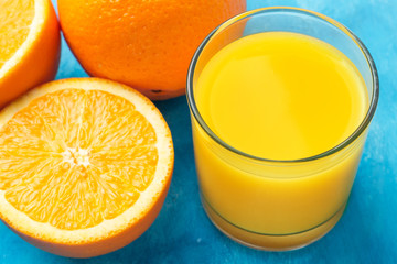 Orange fresh drink, glass of juice and ripe citrus fruits on a blue background