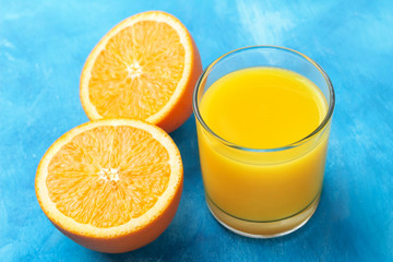 Orange fresh drink, glass of juice and ripe citrus fruits on a blue background