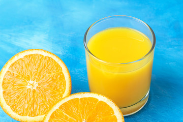 Orange fresh drink, glass of juice and ripe citrus fruits on a blue background