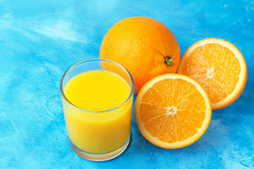 Orange fresh drink, glass of juice and ripe citrus fruits on a blue background