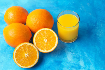 Orange fresh drink, glass of juice and ripe citrus fruits on a blue background