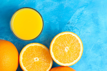 Orange fresh drink, glass of juice and ripe citrus fruits on a blue background, top view