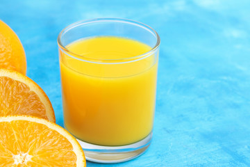 Orange fresh drink, glass of juice and ripe citrus fruits on a blue background