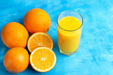 Orange fresh drink, glass of juice and ripe citrus fruits on a blue background