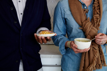 Man and Woman in scarf holding soup and snacks