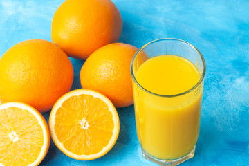 Orange fresh drink, glass of juice and ripe citrus fruits on a blue background