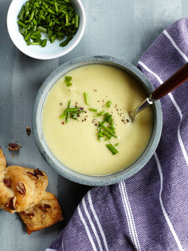 Potato and chive soup in bowl with chives and garlic knot