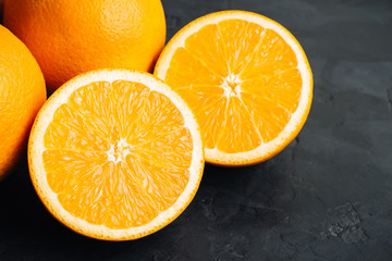 Orange, ripe citrus fruits and round slice on a black, textured background