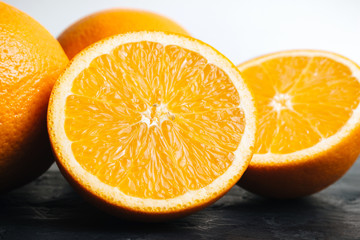 Orange, ripe citrus fruits and round slice on a black, textured table and white background