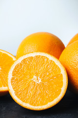 Orange, ripe citrus fruits and round slice on a black, textured table and white background