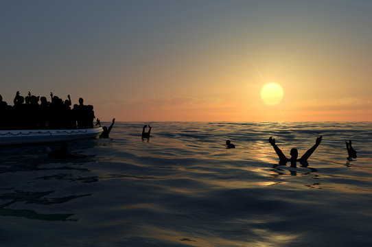 Profughi su un grande gommone in mezzo al mare che richiedono aiuto. Mare con persone in acqua che chiedono aiuto. Migranti che attraversano il mare