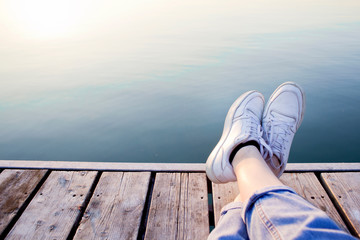 Sporty woman stretched her feet up on a wooden jetty.