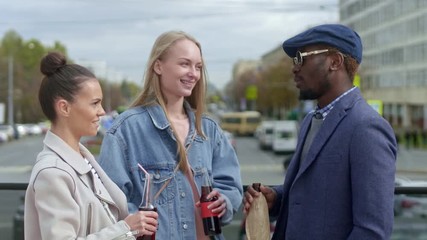 Tilt-up shot of young people standing on the street talking and holding bottles with drinks