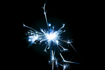 Obraz premium Low light photo of bengali fire isolated on black background with blue toning. A lot of light and sparks. Underexposed photo.