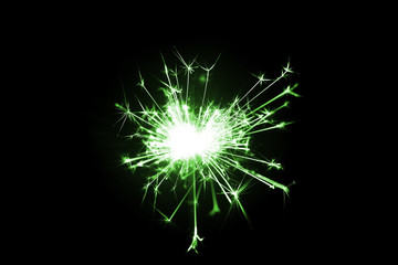 Fototapeta premium Low light photo of bengali fire isolated on black background with green toning. A lot of light and sparks. Underexposed photo.