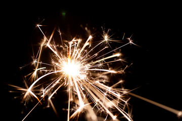 Low light photo of bengali fire isolated on black background. A lot of light and sparks. Underexposed photo.