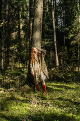 Young woman with long red hair in a linen dress gathering mushrooms in the forest in the bast basket